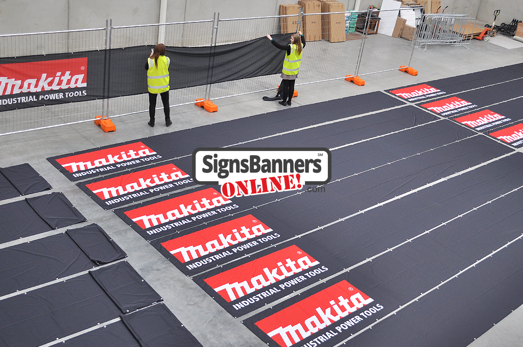 Big banners produced in bulk. People fitting and inspecting the printed banner signs inside the factory for ship out to Makita Promotional Events