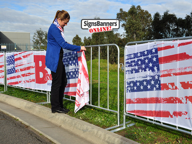 Showing the picture quality of the printed Sports Mesh as used for Baltimore events and public display steel barricades. The young lady is fitting the banner sign to the barricade