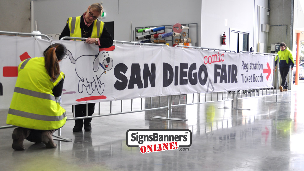 Event graphics team putting up the San Diego banner signs on the temporary event fence covers pre ship out.