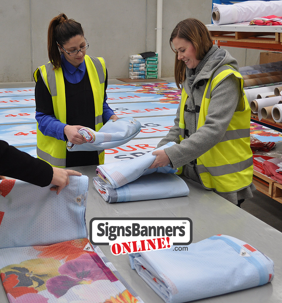People inspecting the banner signage prints and grommets pre-delivery