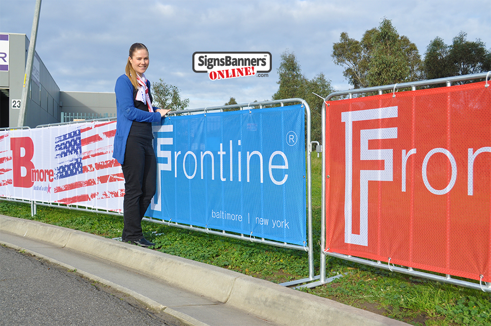 Young lady (wearing USA scarf) standing outside next to the event sign banners on a series of hire rent portable fence crowd barricade steel frames that are upright.