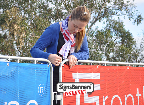 Person putting banners on a fence portable system as used at events, festivals and crowded spaces