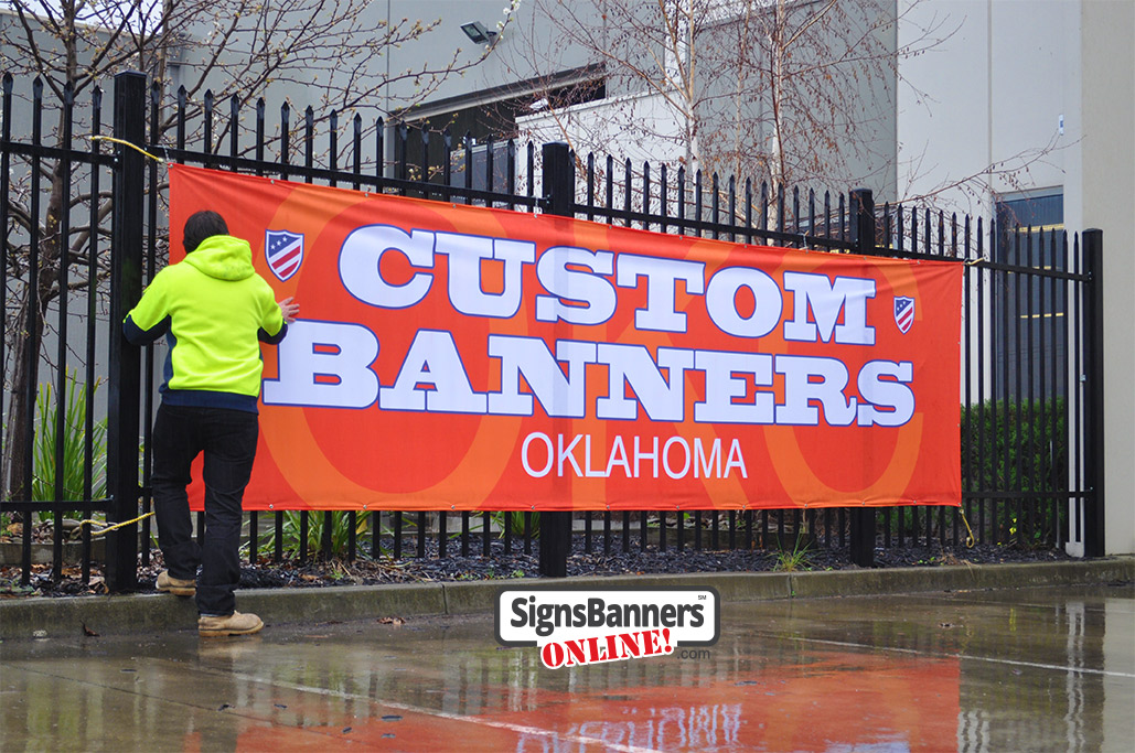 Outdoor banner signs and sign making services, this large banner sign (custom) is outside in the rain. Words are Custom Banners Oklahoma